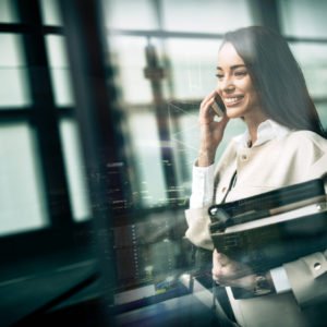 Businesswoman using phone and holding folders