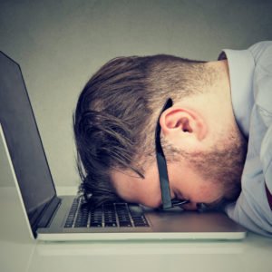 Overworked man lying on laptop