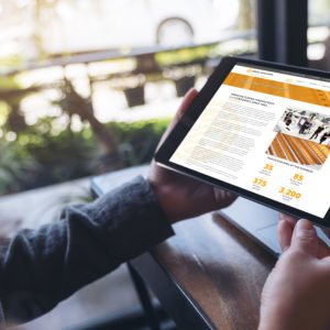 Mockup image of hands holding black tablet pc with white blank screen and laptop on wooden table background in cafe