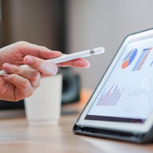 close up salesman employee hand using stylus pen to pointing on tablet screen to show company profit monthly in the meeting event at conference room , business strategy concept